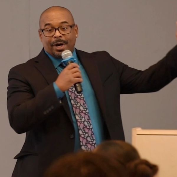 Man in a suit speaking with a microphone.