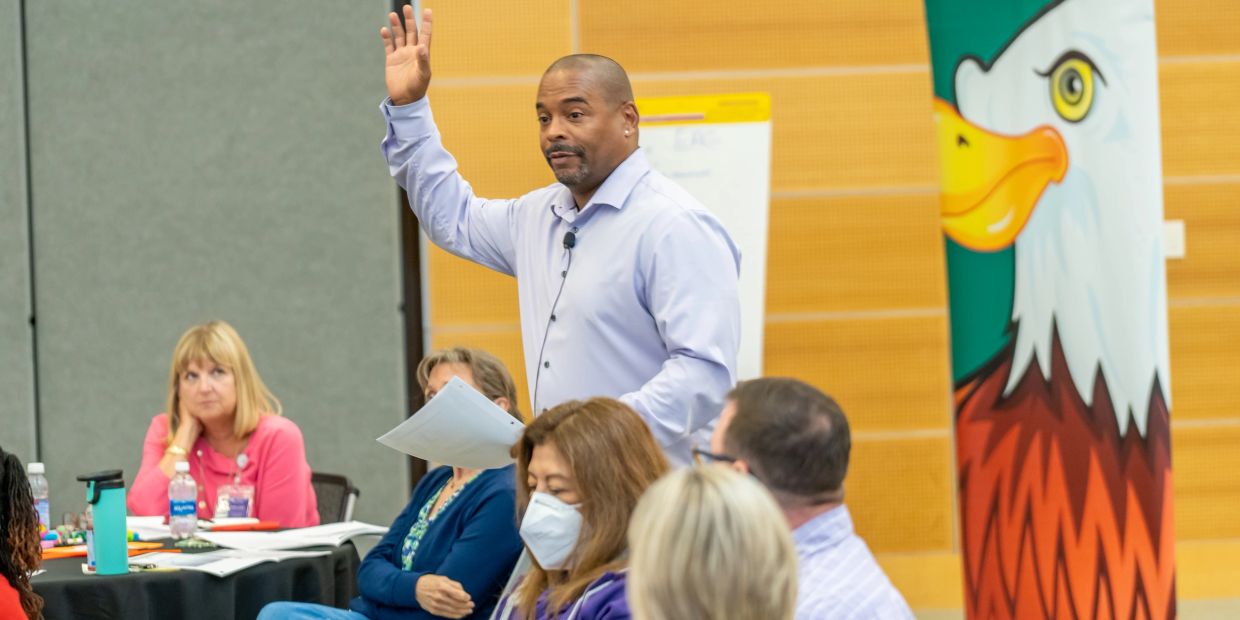 Man speaking and raising hand in a meeting.