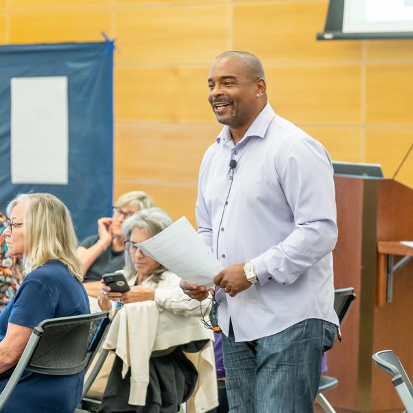 Man speaking and smiling at a seminar or workshop.