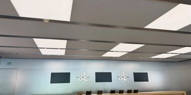 Modern room with large ceiling lights and a row of chairs against the wall.