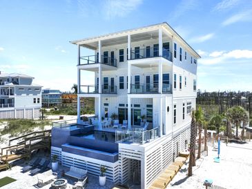 Modern three-story white beach house with balconies and infinity pool.
