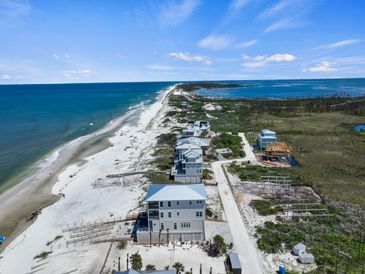 Aerial view of beach houses along a sandy coastline under a clear sky.
