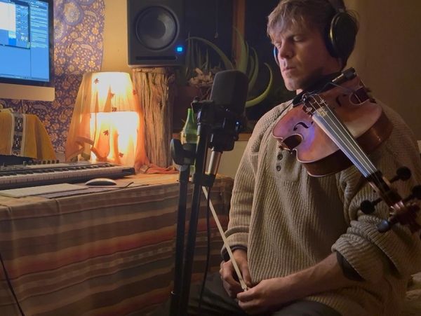 Man playing violin in a recording setup.