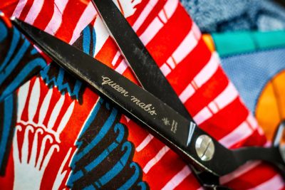 Close-up of black scissors on colorful fabric.