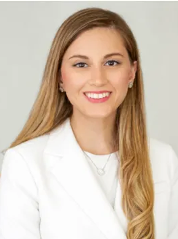 Young woman in white blazer smiling.