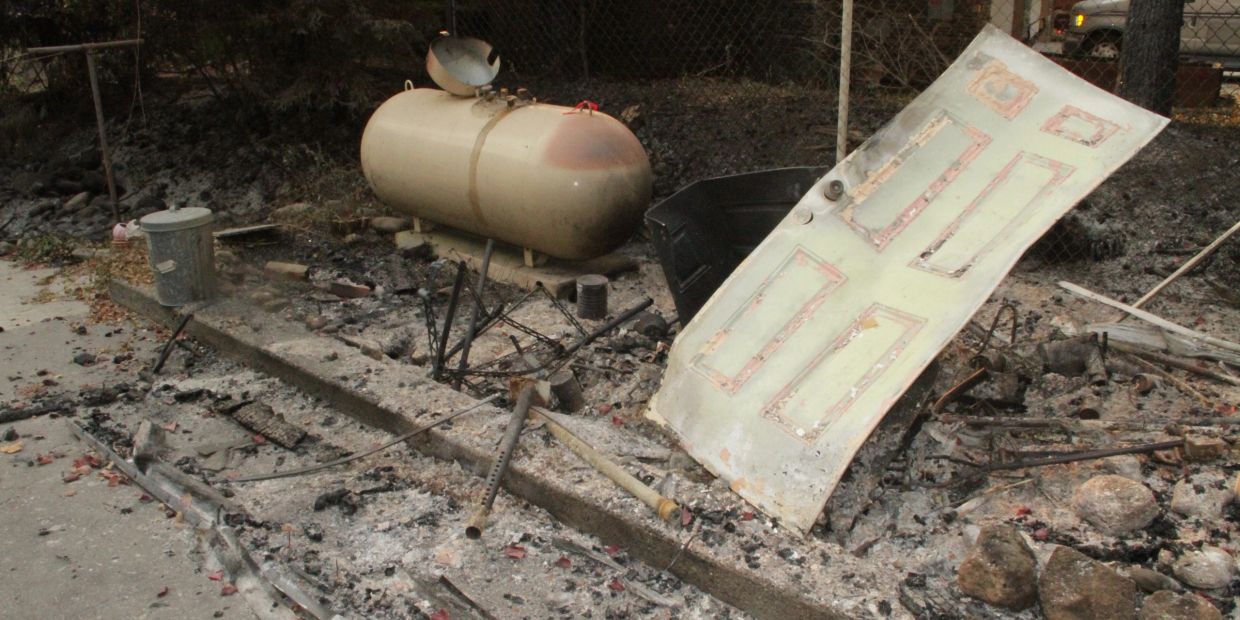 Burned debris including a detached door and propane tank.