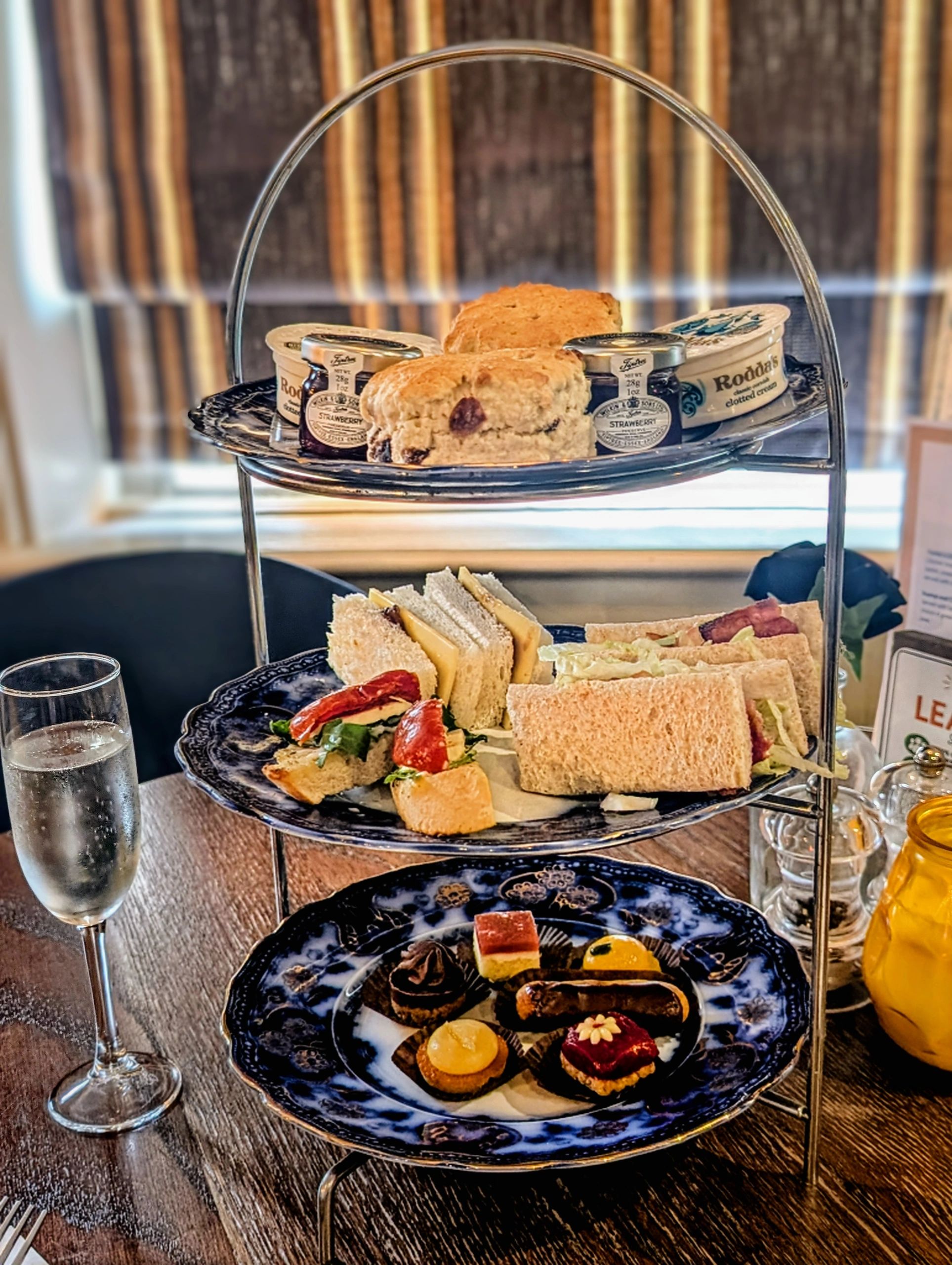 Elegant afternoon tea stand with scones, sandwiches, and desserts.