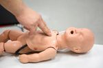Person practicing infant CPR on a training mannequin.