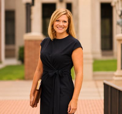 Smiling woman in a black dress standing outdoors.