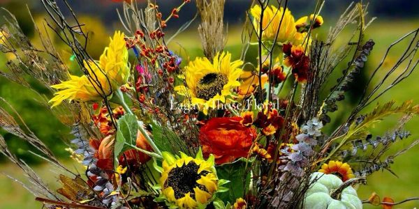 Autumn floral arrangement with sunflowers and pumpkins at sunset.