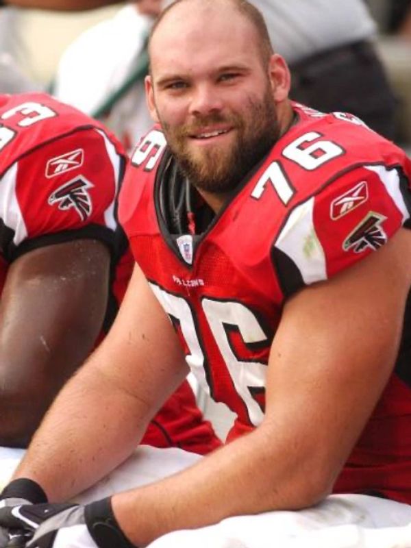 Smiling football player in red Falcons jersey number 76 sitting on bench.