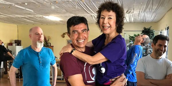 Smiling people in a dance studio, one couple embraces joyfully.