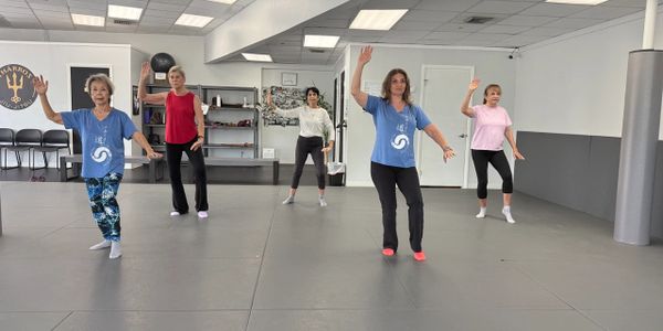 Five women practicing synchronized dance moves in a studio.