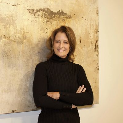 Woman in black sweater stands smiling with arms crossed.