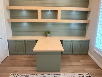 Custom built office including floating shelves with lighting, cabinets and custom built island desk 
