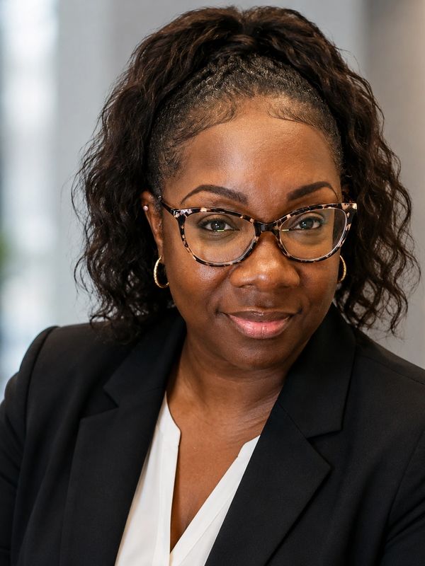Confident woman with glasses and a black blazer.