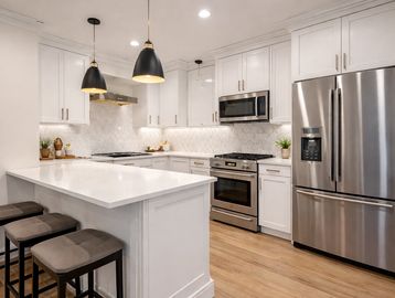 Modern white kitchen with stainless steel appliances and a breakfast bar.
