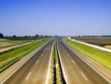 Open four lane highway, free of cars, stretching into the blue sky horizon. 
