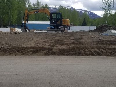 Excavator prepping driveway grade before spreading gravel