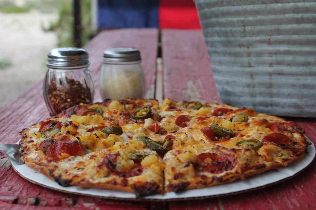 Pizza and condiments on picnic table