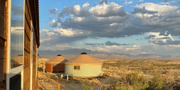 Side view of Loft, Sage and Cinnabar yurts, and colorful clouds over Big Bend