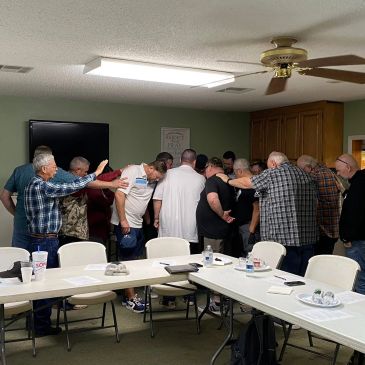 Group of men praying together in a room.