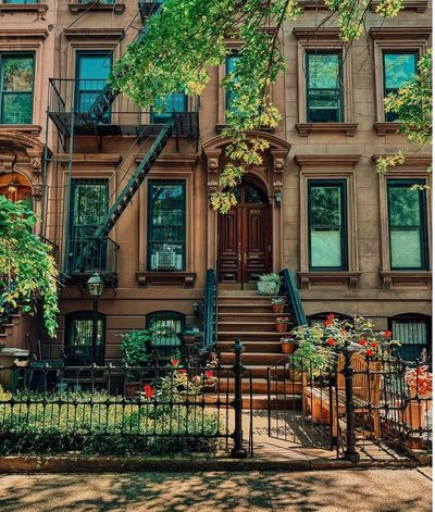 Classic brownstone building with stairs and greenery.