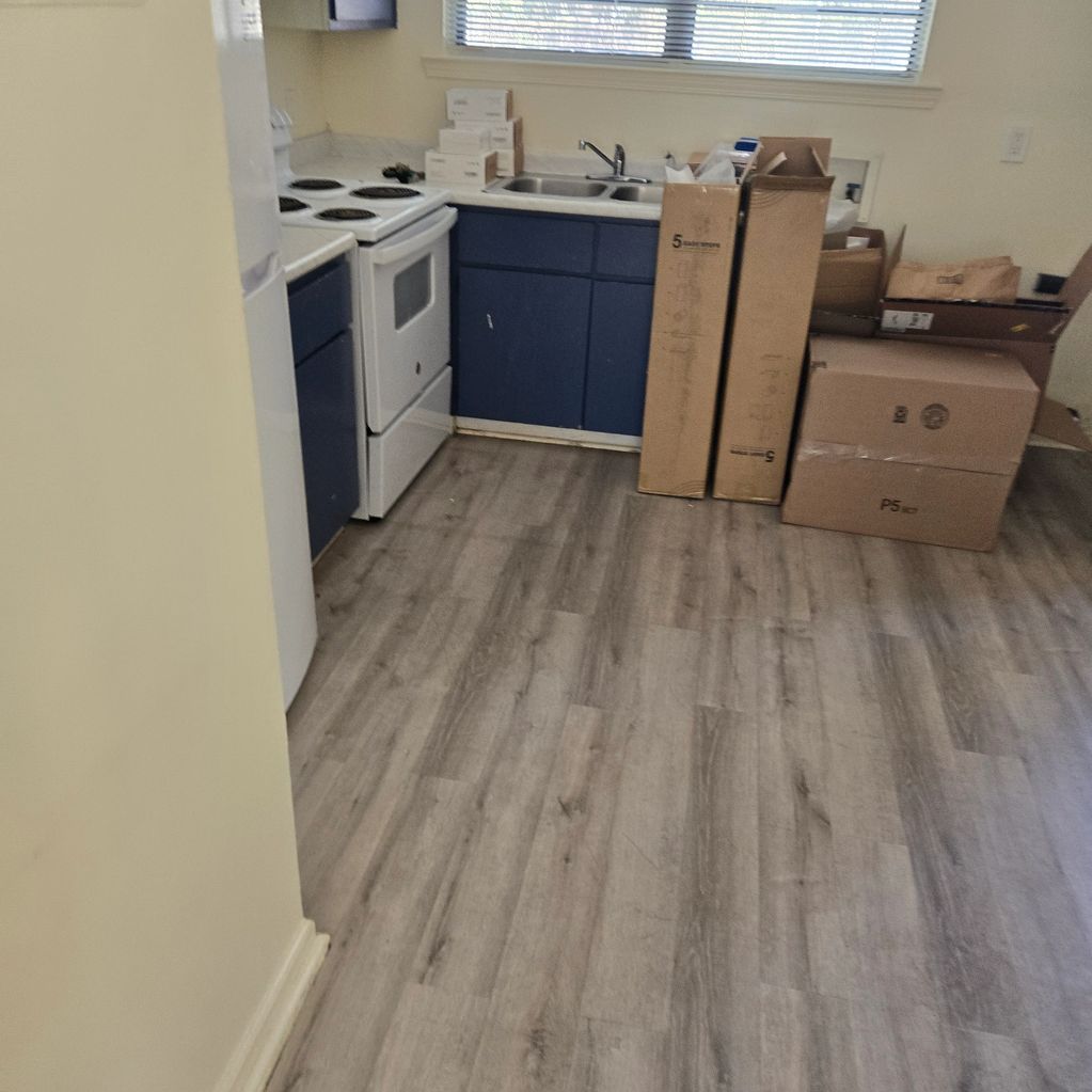 Small kitchen with blue cabinets and boxes near the sink area.
