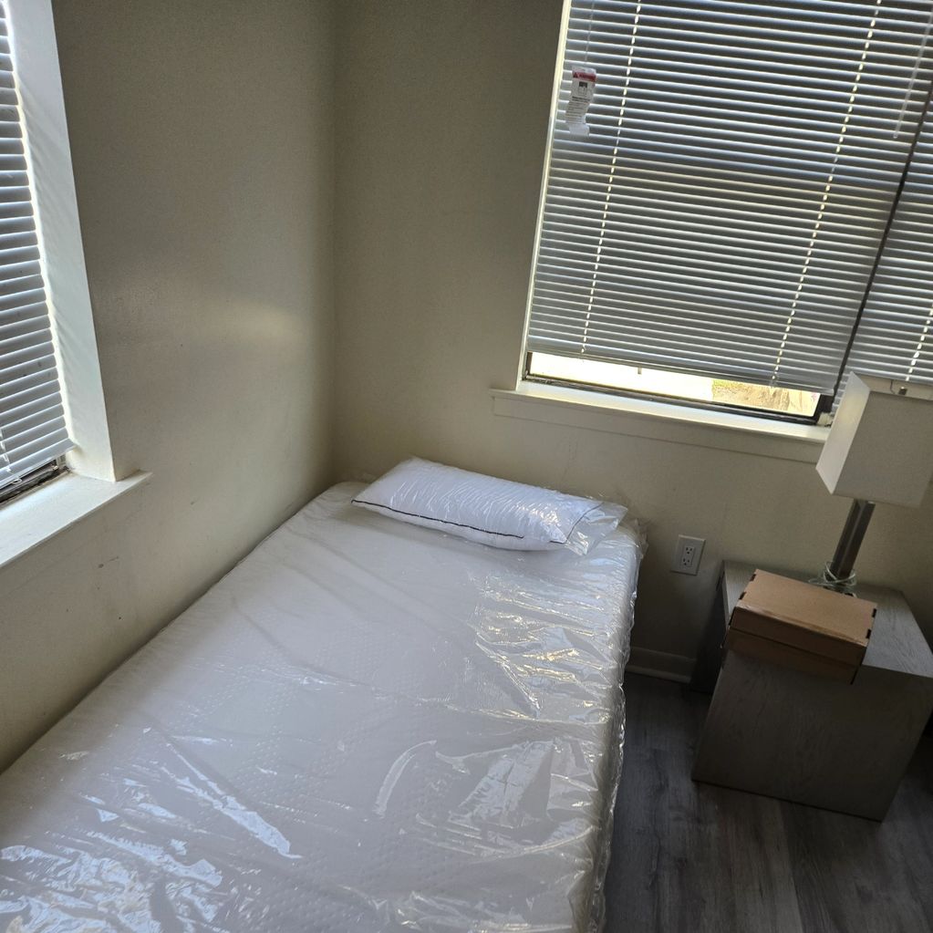 Minimal bedroom with a single bed and a bedside table with a lamp.