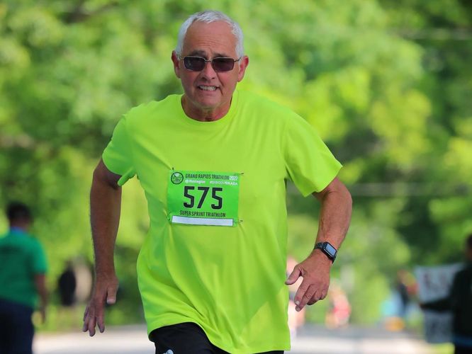 Silver-haired man running in sunglasses wearing a neon green shirt and black shorts
