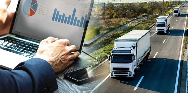 A person analyzing data on a laptop with trucks driving on a highway.