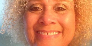 Close-up of a smiling woman with curly blonde hair.