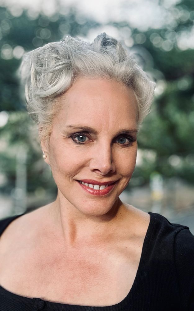 Smiling mature woman with short gray hair outdoors.