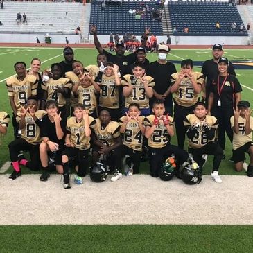 Youth football team posing on the field after a game.