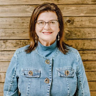 female counselor smiling 
and standing in front of a wood wall