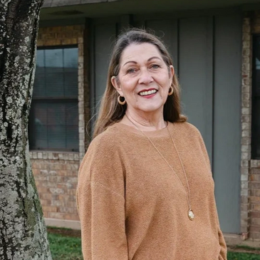 female counselor smiling and standing in front of a tree 