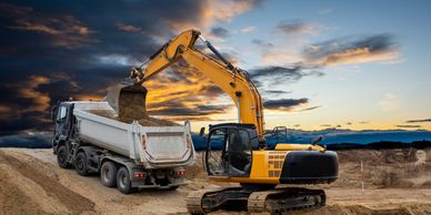 An excavator and dump truck engaged in Trucking and hauling Dirt