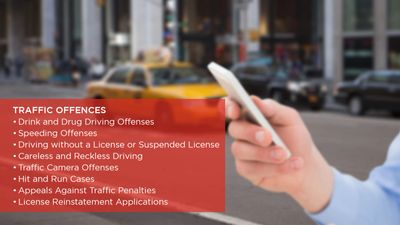 Hand holding a smartphone with traffic offences listed in a red box.