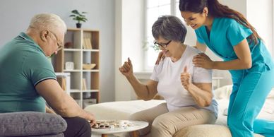 Elderly couple playing a board game with a caregiver's support.