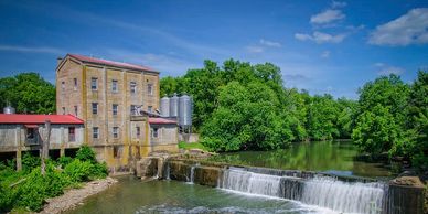 Old mill building by a river and waterfall.