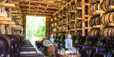 Barrel storage room with leather chairs and drinks.