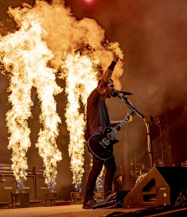 A massive wall of flames bursts behind Godsmack frontman Sully Erna. 