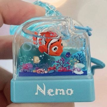 A small Finding Nemo aquarium toy held by a hand.