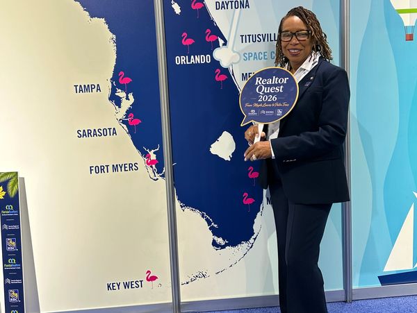 Woman in business suit holding Realtor Quest 2026 sign in front of Florida map.