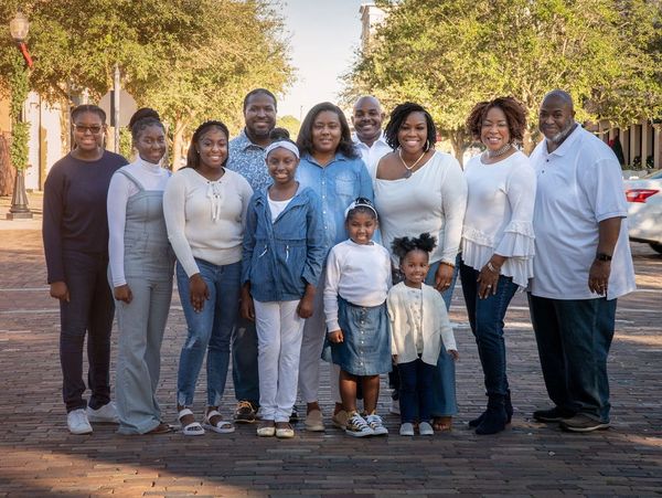 A large family posing together outdoors on a sunny day.