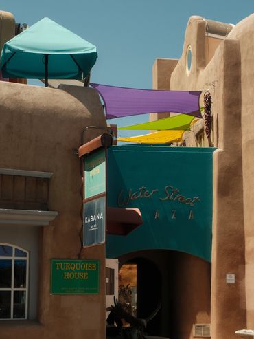 Colorful shaded walkway in Adobe-style architecture under clear sky.