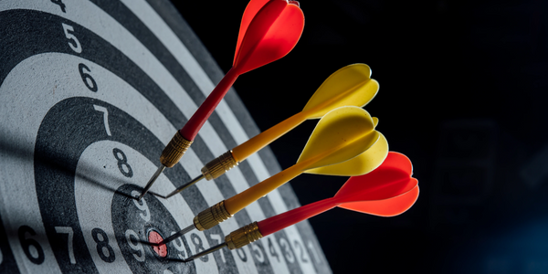 Four darts hit the bullseye on a dartboard.