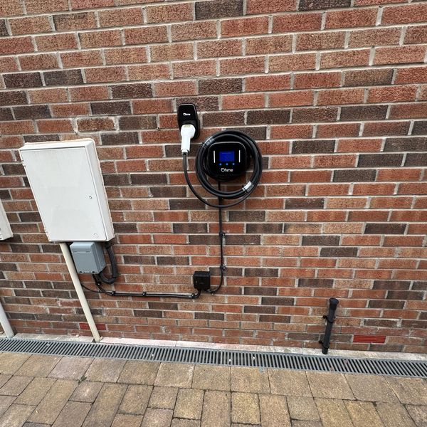 Electric vehicle charging station mounted on a brick wall outdoors.