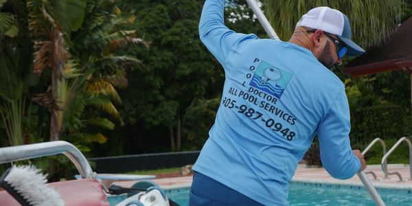 Pool tech servicing a pool with Pool Doctor of South Florida logo.