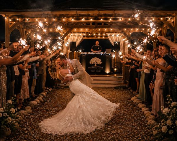 Newlyweds kiss under a sparkling send-off at night.